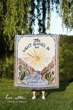 a woman standing in the grass holding up a sign that says light shines in