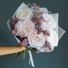 a person holding a bouquet of white and pink flowers