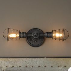 an old fashioned light fixture with two lights on it's side and the wall behind it