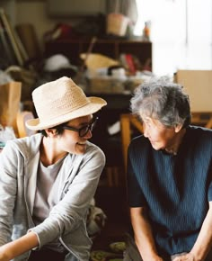 an older woman sitting next to a younger woman in a room full of clutter