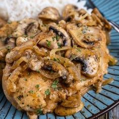 a blue plate topped with meat and mushrooms covered in gravy next to rice