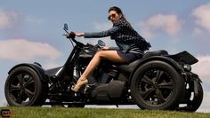 a woman riding on the back of a motorcycle down a grassy hill with clouds in the background