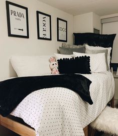 a bed with black and white comforters in a bedroom next to pictures on the wall