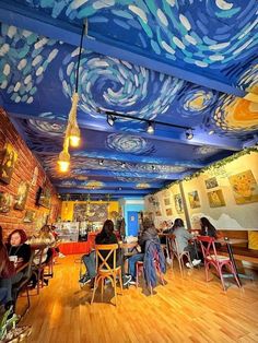 people sitting at tables in a room with paintings on the ceiling