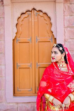 a woman dressed in red and gold poses for the camera