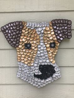 a dog made out of bottle caps on the side of a house