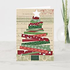 a card with a christmas tree made out of ribbon on top of sheet music paper