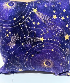 a purple and gold pillow with stars and planets in the sky on top of it