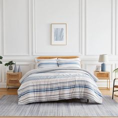 a bed with blue and white striped comforter on top of it in a room