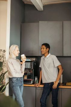 a man and woman standing in front of a coffee machine