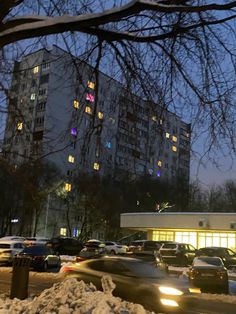 cars are parked on the side of the road in front of tall buildings at night