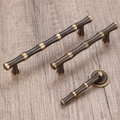 three brass door knobs and two handles on a wooden surface with wood grained flooring