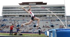 a man is jumping in the air with a long pole on his feet while people watch from the bleachers