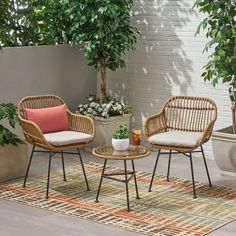 two wicker chairs sitting on top of a rug next to a potted plant