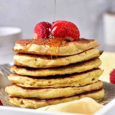 a stack of pancakes with syrup and strawberries