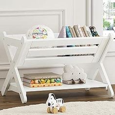 a white children's book shelf with books and toys on it in front of a window