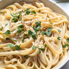 a white bowl filled with pasta and garnished with parsley