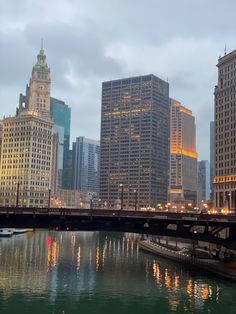 the city skyline is lit up at night, with skyscrapers reflected in the water