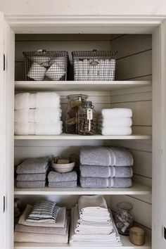 an organized linen closet with folded towels and baskets