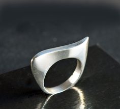 Elegant classic ring featuring a modernist wave design. The ring's fluid curves make an abstract art statement and it has a beautiful handmade look and feel. The ring's inner diameter is about 18.14, making the size a US size 8. The band measures 4 mm wide and is marked 925. The silver band has a few tiny nicks and scratches, consistent with wear and age. When wearing the ring, you don't notice these scratches - what you notice is the beauty of the ring's design and the excellent craftsmanship. Please zoom in each picture to see the tiny dings and scratches that are naturally acquired over time. These can be polished out, however, such marks are part of the ring's history and I'd recommend that you leave the marks and add your own personality and history to the piece :)  The pictures in my Modern Wavy Rings With Polished Finish, Modern Silver Wavy Rings, Modern Curved Rings With Polished Finish, Modern Wavy Jewelry For Formal Occasions, Modern Curved Jewelry With Polished Finish, Wax Tutorial, Abstract Ring, Modern Silver Ring, Art Statement