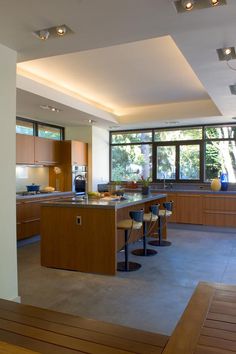 an open kitchen and dining room area with wood cabinets, counter tops, and bar stools