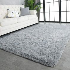 a living room with a white couch and gray rugs on the floor in front of a large window