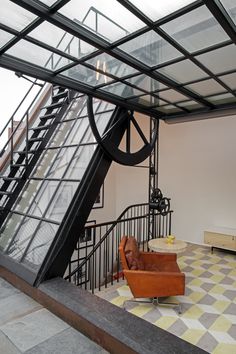 a chair sitting on top of a tiled floor next to a stair case with a glass door