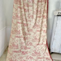 a red and white toiler print blanket hanging on a wall in a room