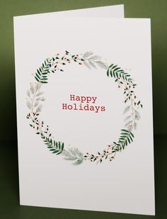 a white card with the words happy holidays written in red and green leaves on it