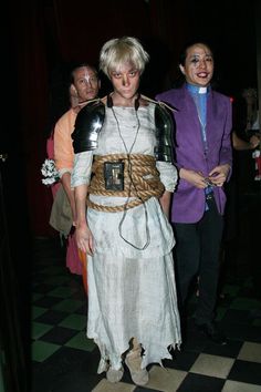 two people dressed in costumes standing next to each other on a checkerboard floor