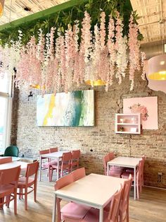 the interior of a restaurant with pink chairs and flowers hanging from the ceiling over the tables