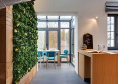 a room with a table and chairs covered in green plants next to a kitchen counter