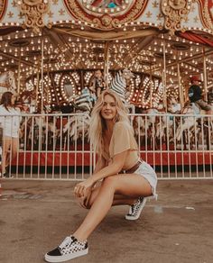 a woman sitting on the ground in front of a merry go round