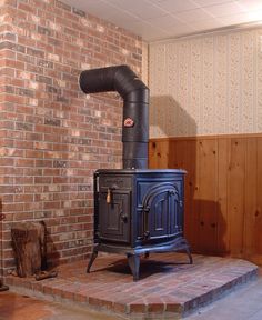 an old fashioned wood stove sitting in front of a brick wall with exposed piping