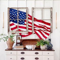 an american flag hanging on the wall next to a dresser with books and vases