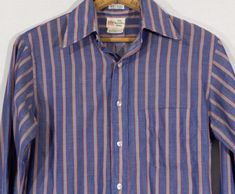 Here's a styling late 60's / early 70's vertical striped oxford button down shirt with a cool University Shop "77" original label. This well tailored shirt has a lovely lightweight permanent press cotton blend textile that's blue on blue with red and yellow offset highlighting. You'll love it's swanky vibe and look real cool in it. This 'Seven Seven' line original is in overall good condition with some pilling and a slight pullin the back that's very hard to notice. The last photo close up show Retro Spring Shirt With Placket, Cotton Shirt With Vertical Stripes For Daywear, 1970s Style Cotton Shirt For Spring, Retro Cotton Shirt With Striped Collar, Vintage Cotton Shirt With Striped Collar, 1970s Fitted Cotton Shirt, Retro Striped Button-up Shirt, Vintage Striped Cotton Shirt, Vintage Striped Summer Shirt