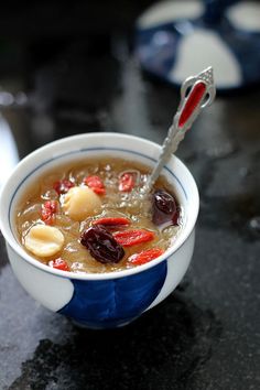 a blue and white bowl filled with soup on top of a counter next to a spoon