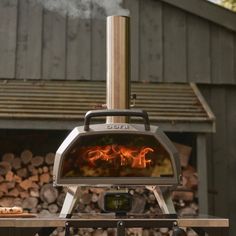 an outdoor wood burning oven with logs in the background