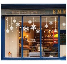 a store front with snowflakes on the windows and decorations hanging from the window