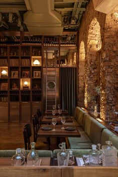 an empty restaurant with tables and chairs in front of bookshelves filled with wine glasses