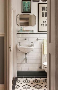 a bathroom with black and white tile flooring and pictures on the wall above the sink