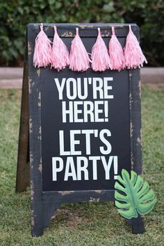 a sign that says you're here let's party with tassels on it