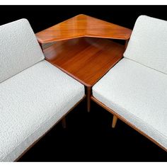 two white chairs sitting next to each other on top of a wooden table in front of a black background