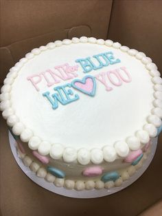 a white cake with pink and blue frosting on top in a cardboard box that says pink & blue, we love you