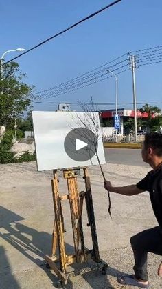 a man is painting on an easel in the street