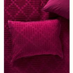 a bed with pink sheets and pillows next to a pillow on top of the bed