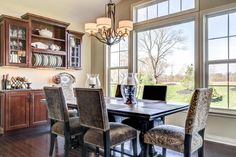 a dinning room table and chairs in front of large windows