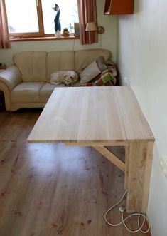 a wooden table sitting in the middle of a living room next to a couch and window