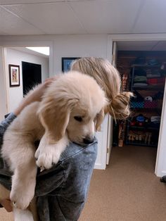 a woman holding a puppy in her arms while sitting on top of someone's leg