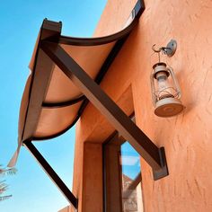 an outdoor light on the side of a building next to a palm tree and blue sky